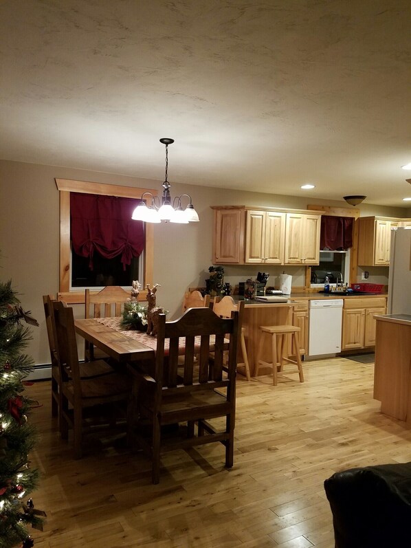 A cozy kitchen with wooden cabinets, a dining table with chairs, and a Christmas tree. - Beautiful House with Mountain Views (Morgan)