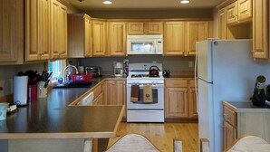 Una cocina con gabinetes de madera, microondas, estufa y refrigerador.