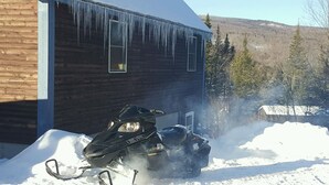 Una moto de nieve estacionada frente a un edificio de madera con cascabeles de hielo colgando del techo.