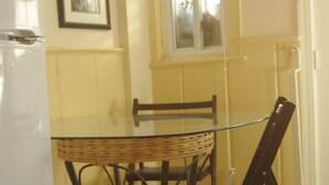 A dining area with a glass table, wicker chairs, and a white refrigerator. - Cozy English Basement Guesthouse (Washington)