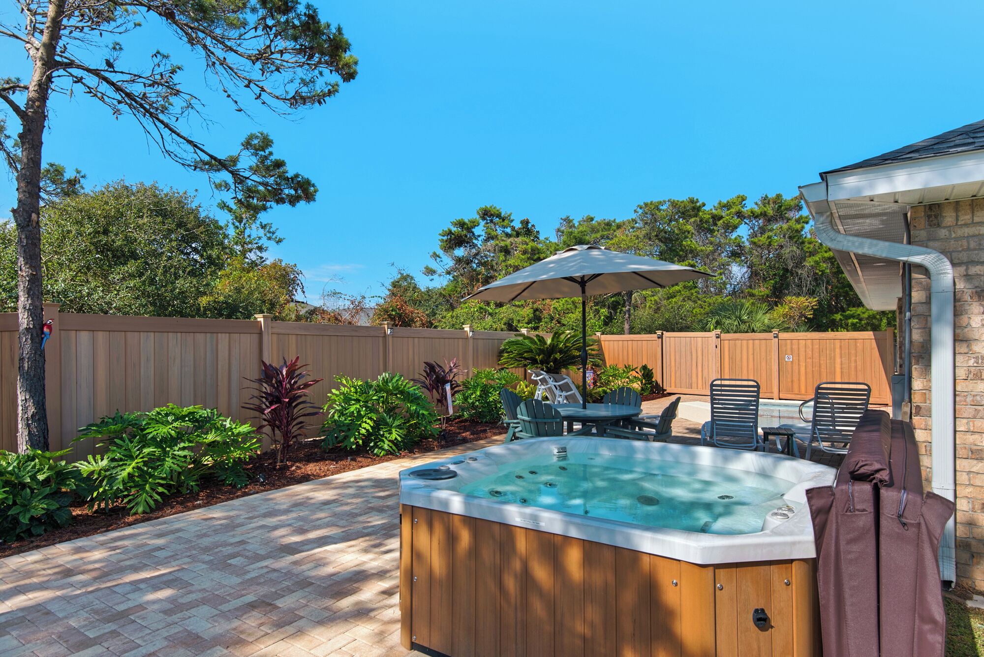 A backyard with a hot tub, patio furniture, and a wooden fence.