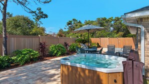 A backyard with a hot tub, patio furniture, and a wooden fence. - Upscale Home, Pool, Hot Tub, EV Charger, Pets OK, 10% Off Golf Cart Rentals (Miramar Beach)
