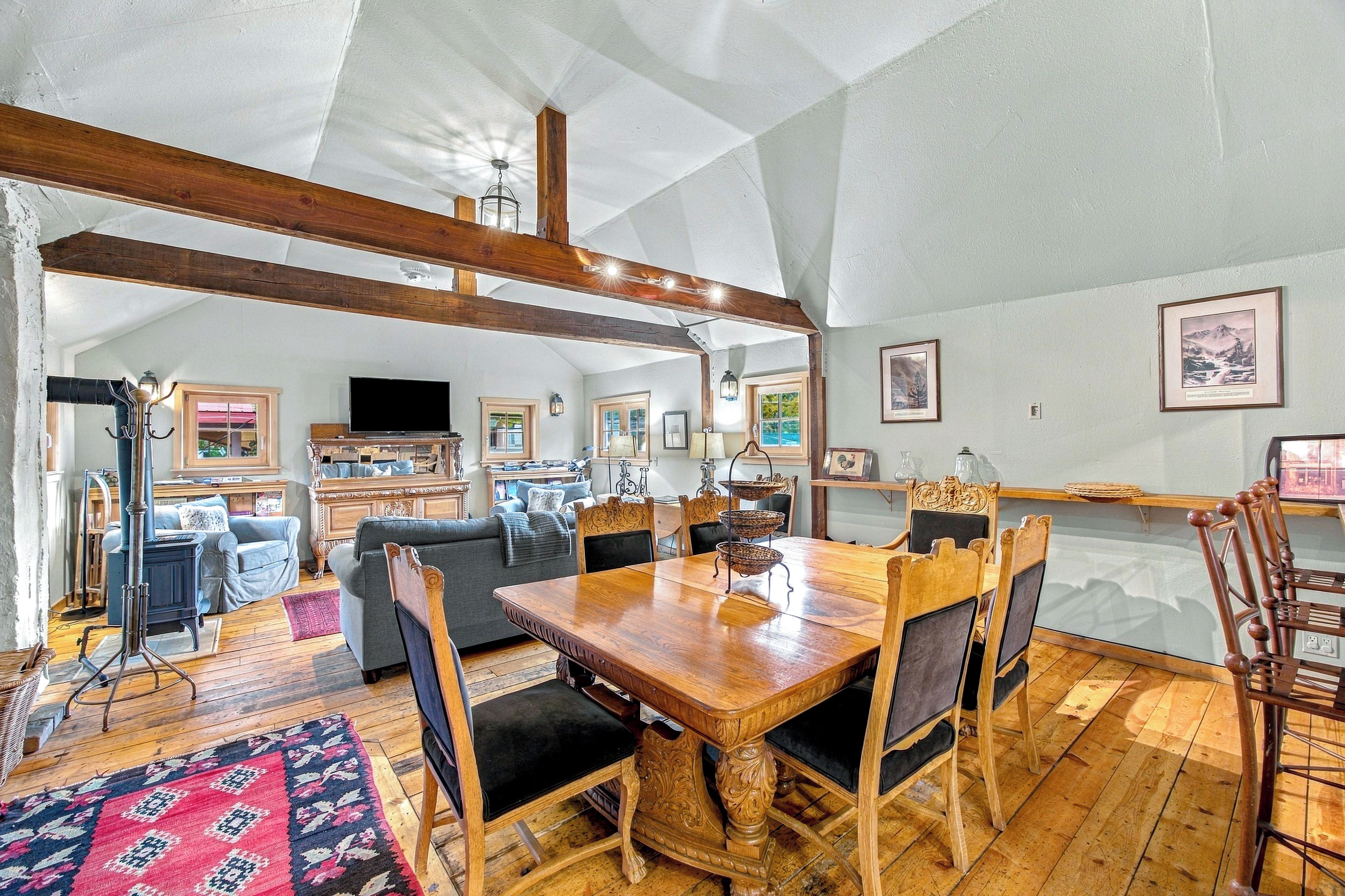 A spacious living area with a wooden dining table, comfortable seating, and a large window providing natural light.