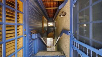 A narrow hallway with blue doors and wooden shutters, leading to a staircase.