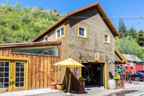 Un edificio rústico con fachada de madera, un ventanal grande y un toldo amarillo.