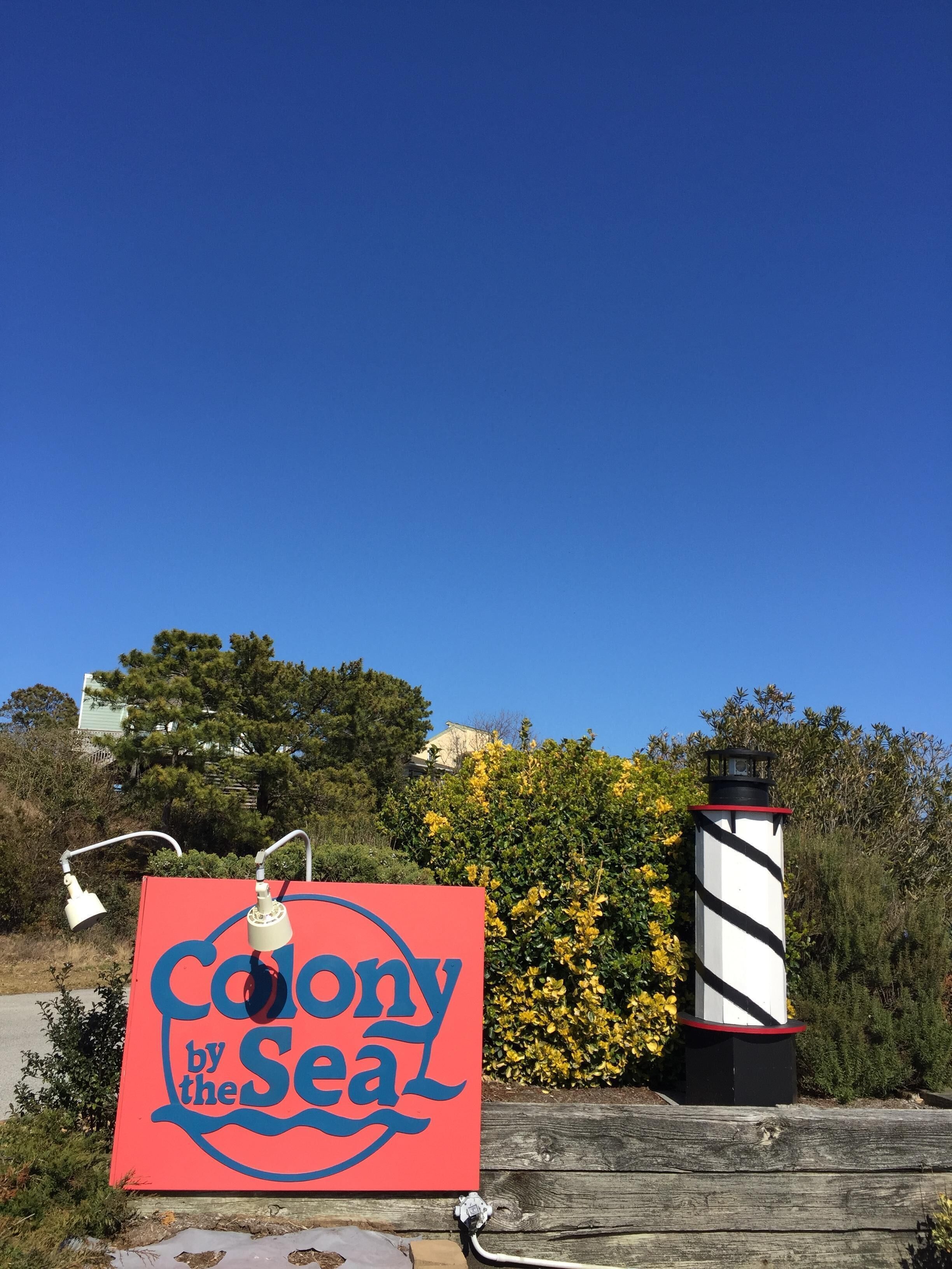 Ein Schild mit der Aufschrift 'Colony by the Sea', im Hintergrund ein Leuchtturm.