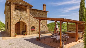 Un bâtiment en pierre doté d’un patio aménagé avec des espaces de détente en plein air et un barbecue.
