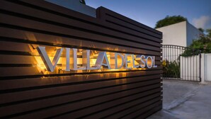 Un letrero con el nombre "VILLADEL SOL" iluminado sobre un fondo de madera.
