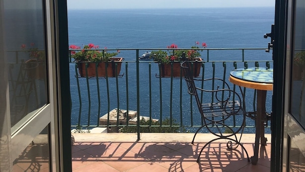 Ein Balkon mit Meerblick, einem Tisch und Blumentöpfen.