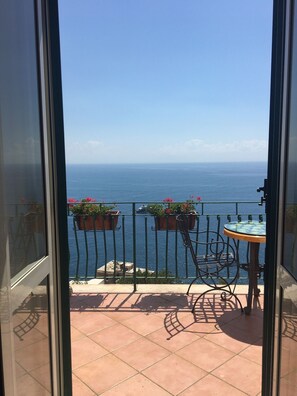 Een balkon met uitzicht op zee, een tafel en potplanten.