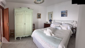 Ein Schlafzimmer mit Bett, Kleiderschrank, Nachttisch, Lampe und einem Bild an der Wand.