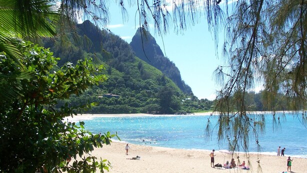 A beach with clear blue water, sandy shore, and lush green hills in the background. - Romantic Cottage, Private Acre of Paradise, View! Pool! (Hanalei)