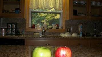 A kitchen with a window, a sink, and two apples on the counter.