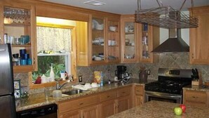 A kitchen with wooden cabinets, granite countertops, a stainless steel refrigerator, and a stove. - Mammaw's Lakefront Cabin bordering The Blue Ridge Parkway (Jefferson)