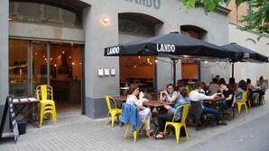 Un espace extérieur aménagé avec des chaises et des tables jaunes, situé devant le restaurant LANDO.