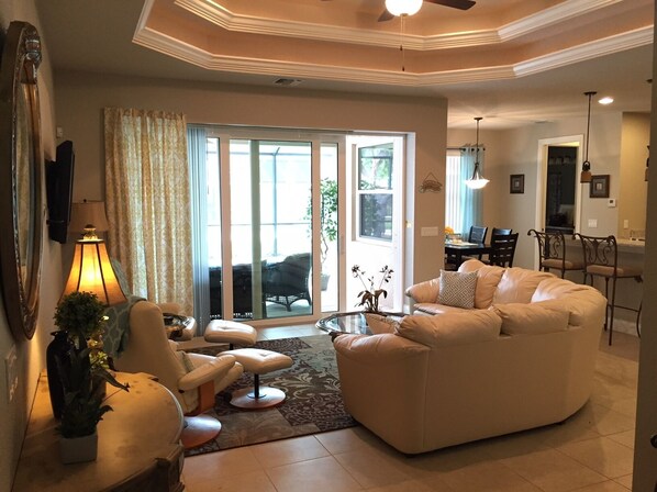 A spacious living room with a large sofa, a coffee table, and a dining area with a table and chairs.