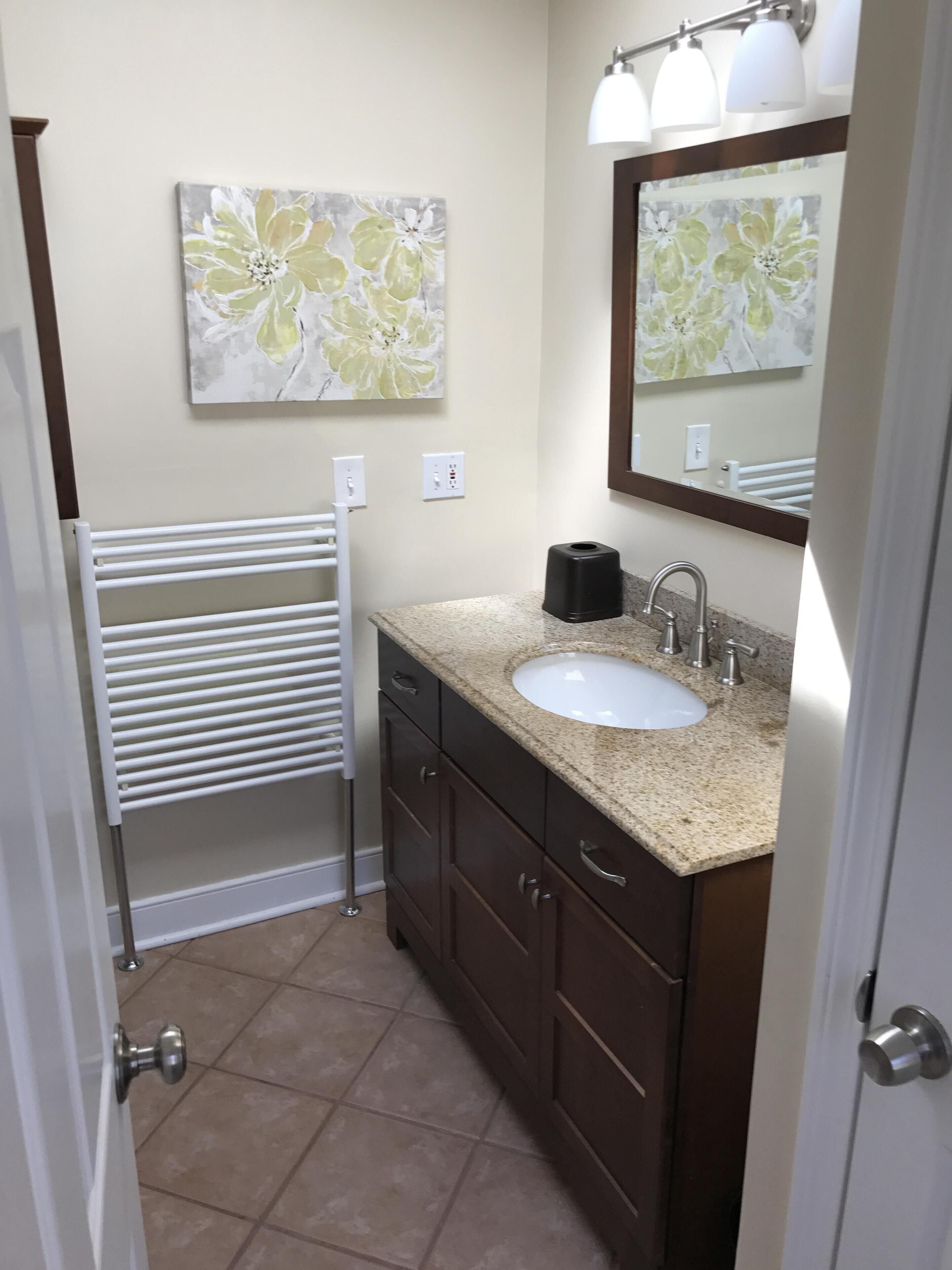A bathroom with a white sink, dark wooden cabinets, a towel rack, and a mirror with a light fixture.
