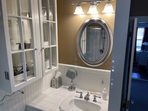 A bathroom with a white sink, three faucets, a mirror, and a towel dispenser. - Falcon's Nest—Beautiful In-Town Bar Harbor Home, Walk to Downtown, Pet Friendly (Bar Harbor)