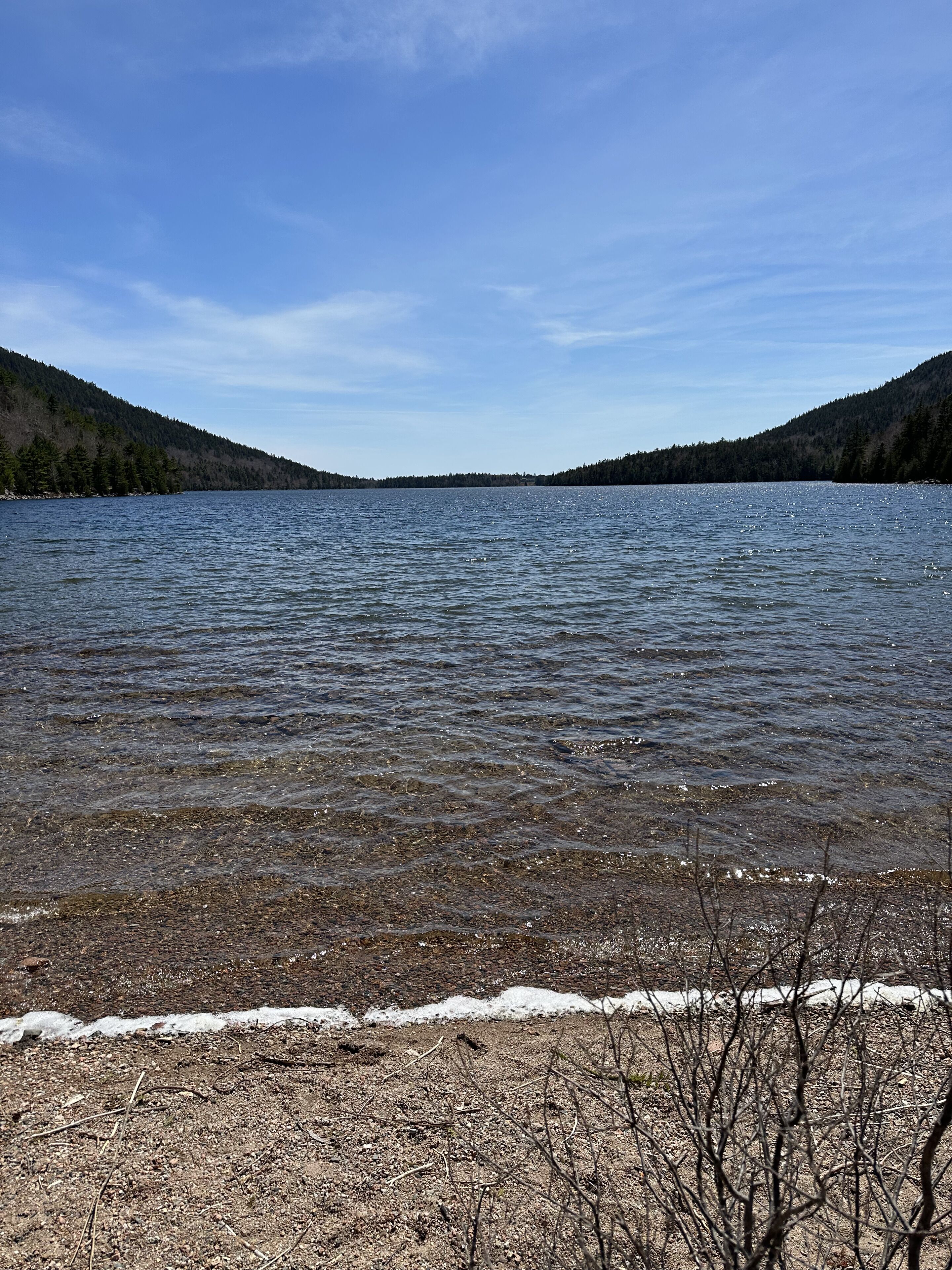 A lake with a clear view of the surrounding forested hills.