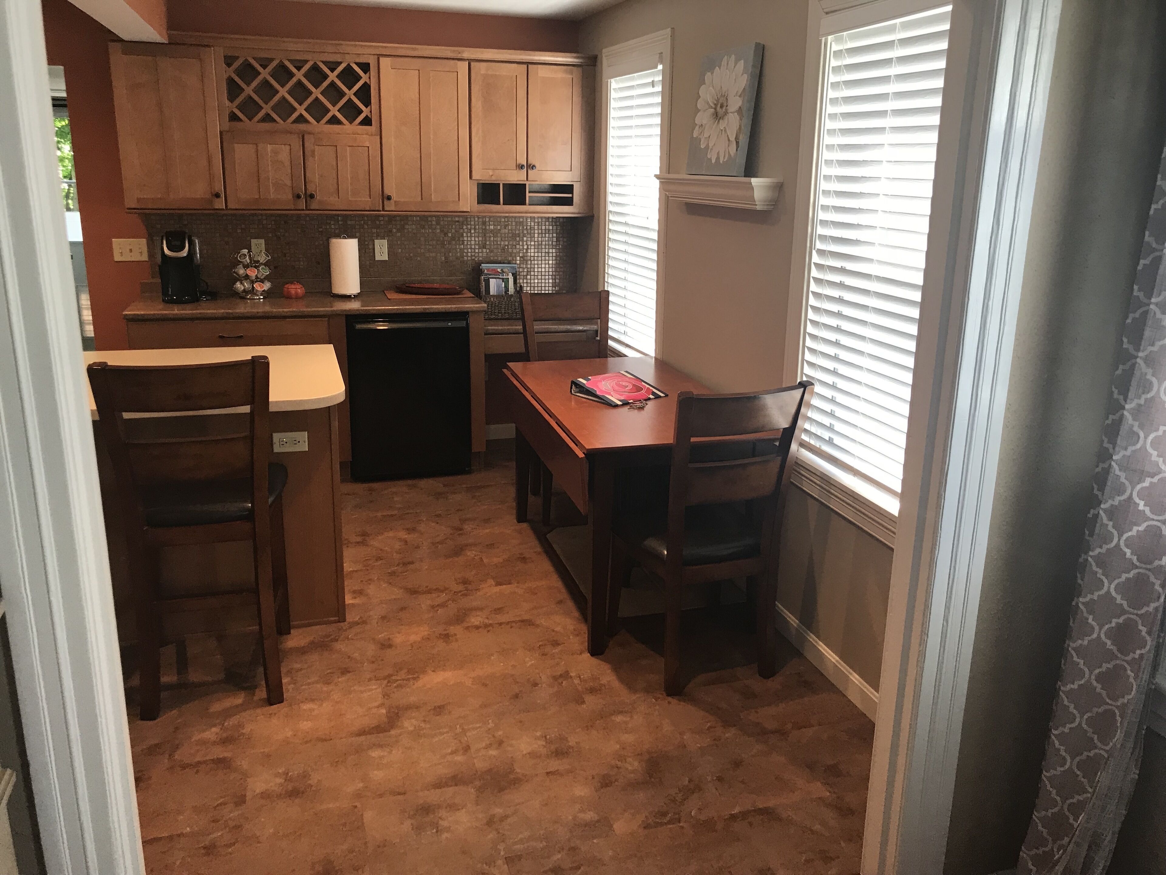 A compact kitchen with wooden cabinets, a dining table, and chairs.