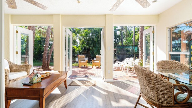 A spacious room with a wooden coffee table, wicker chairs, and a glass dining table. - Gulf Breeze (Naples)