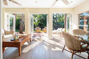 A spacious room with a wooden coffee table, wicker chairs, and a glass dining table. - Gulf Breeze (Naples)
