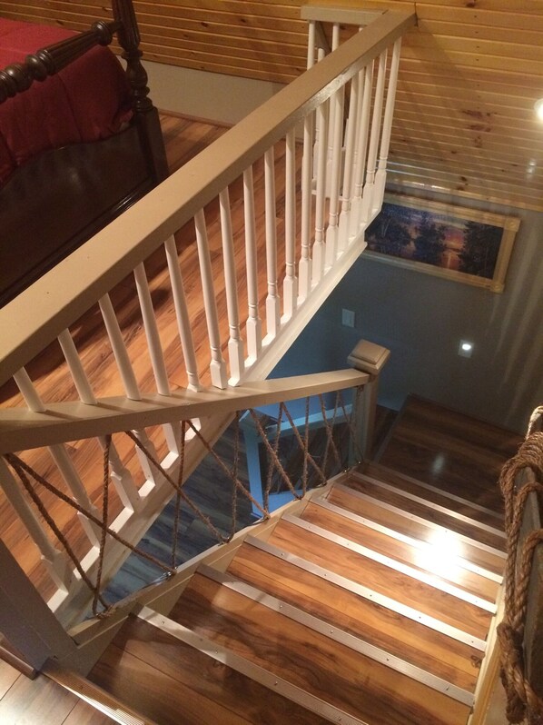 Una escalera de madera con barandillas blancas que baja a un nivel inferior.