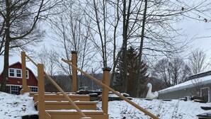 Un escalier en bois menant au sommet d’une colline enneigée, avec un cygne visible au loin.
