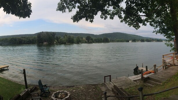 Une jetée au bord du lac, avec un foyer, une terrasse en bois et un petit bâtiment doté d’un toit rouge.