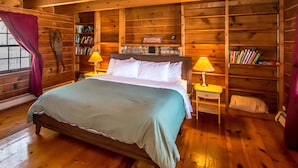Una habitación de madera con una cama, estanterías y dos lámparas.