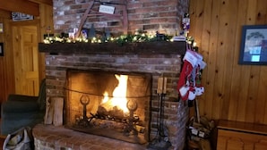 Una chimenea con revestimiento de ladrillo, un letrero encima que dice “SKIL LIFT” y una decoración navideña en la repisa.