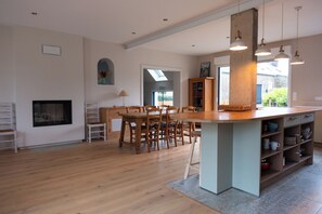 A spacious kitchen with wooden flooring, a central island, and pendant lighting.