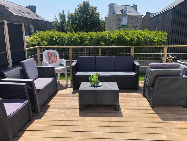 An outdoor patio with wicker furniture, a white chair, and a small table with a plant. - ☼ Villa Cancalune | Walk to the Sea & Town | Pool Table + Foosball | Sleeps 15 ☼ (Cancale)