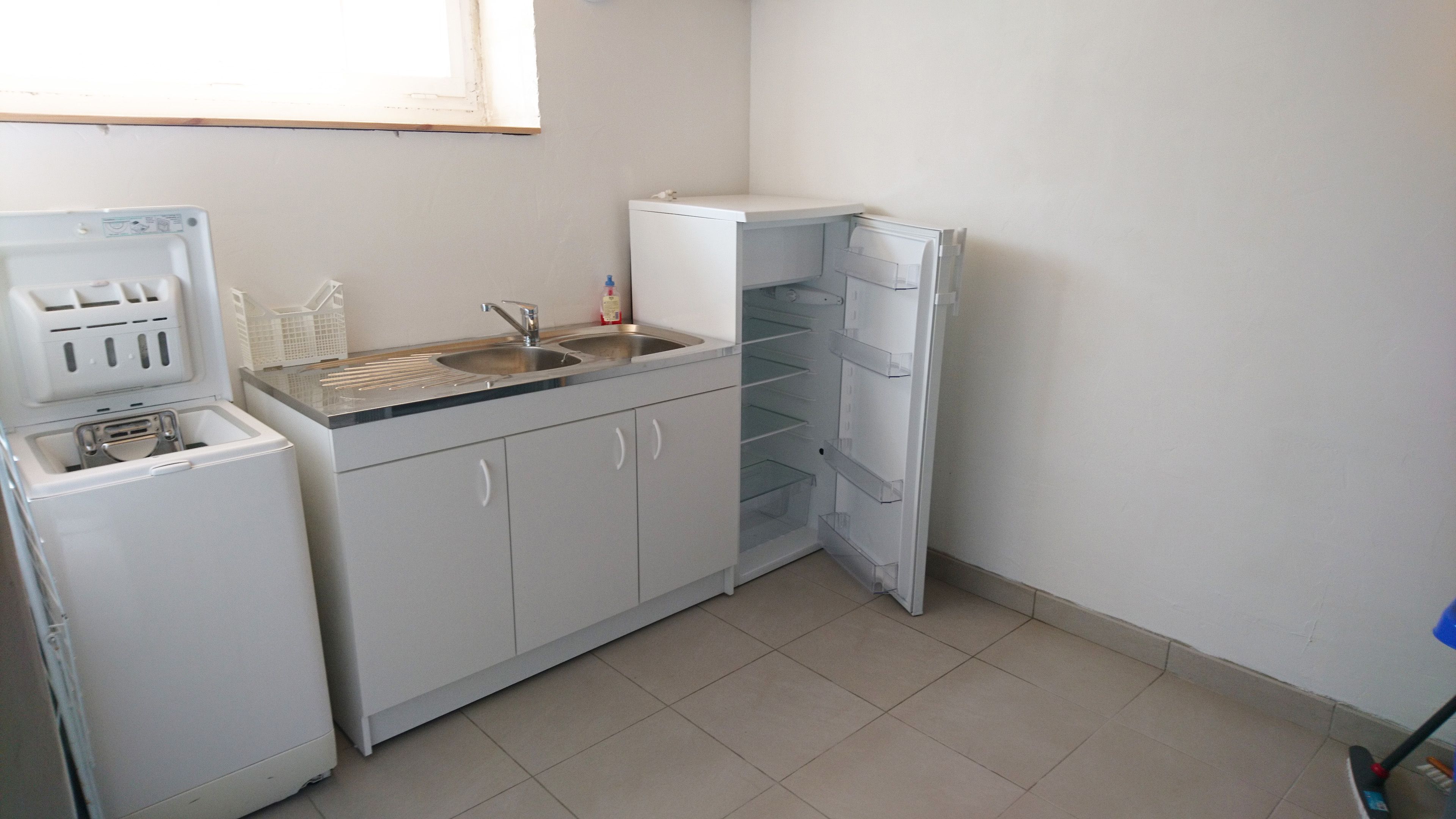 A compact kitchen with a built-in washing machine, a sink, and a refrigerator.
