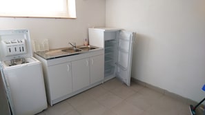 Cocina funcional con lavadora integrada, lavaplatos y refrigerador.