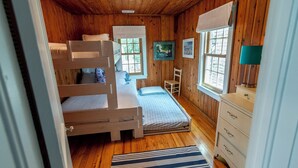 A wooden cabin room with bunk beds, a desk, a chair, and a dresser. - Classic Pawleys. Just Renovated. Long, breezy porches. Steps to beach and creek. (Pawleys Island)