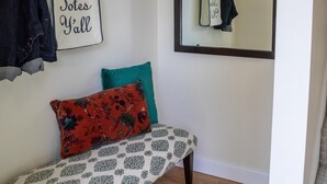 A room with a bench, a mirror, a coat rack, and a wall-mounted sign.