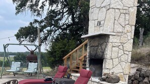 Un bain à remous avec des chaises longues rouges, une cheminée en pierre et une terrasse en bois.