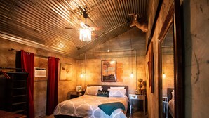 Une chambre confortable avec un lit, un plafond en bois, un lustre et un miroir.