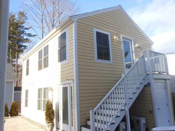 A two-story house with a white exterior, a front door, and a staircase leading to the second floor.