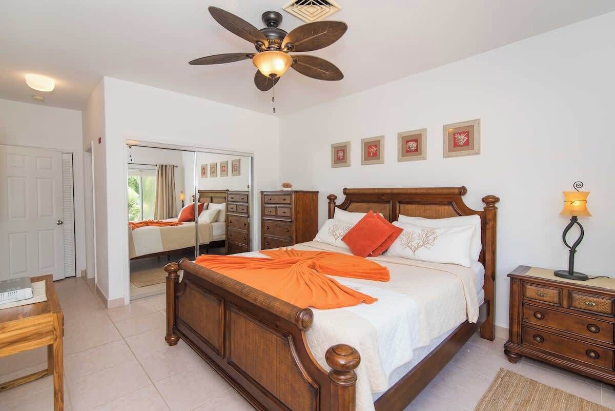 Un dormitorio con cama de madera, ventilador de techo, mesita de noche y espejo.