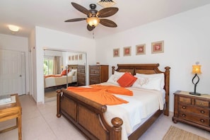 A bedroom with a wooden bed, a ceiling fan, a nightstand, and a mirror.