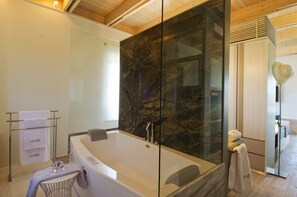 Een bad/douchecombinatie, een bubbelbad, een haardroger, handdoeken