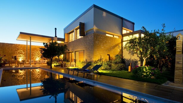 Een modern huis met een zwembad, buitenmeubels en een tuin.
