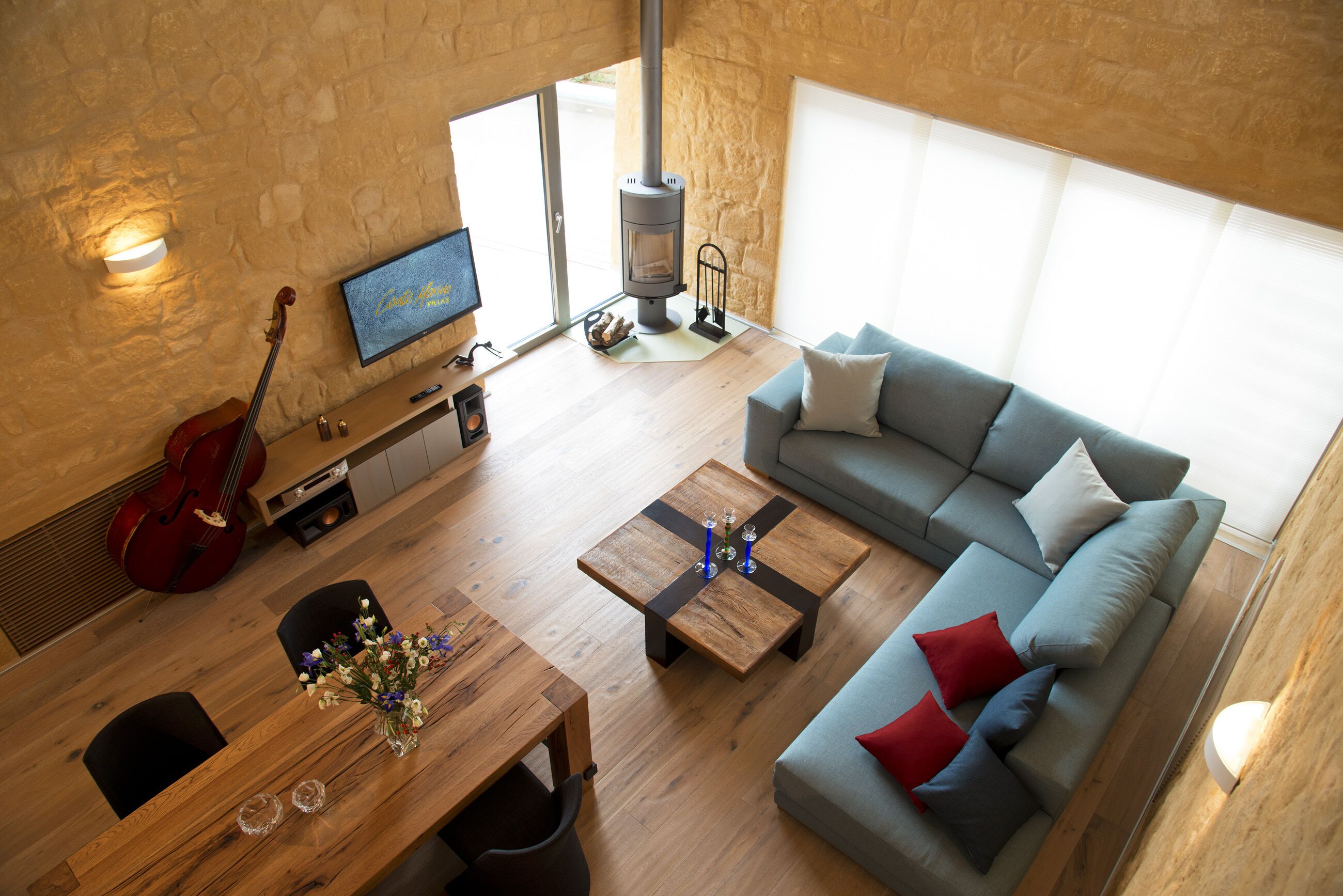 A modern living room with a sofa, coffee table, TV, fireplace, and a red guitar.