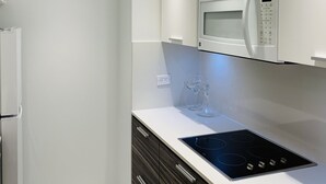 Een moderne keuken met witte kastjes, een ingebouwde magnetron, een oven en een zwart inductiekookplaat.