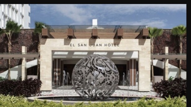 De ingang van Hotel El San Juan, met een grote decoratieve bol op de voorgrond.