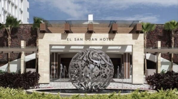 The entrance of El San Juan Hotel with a large decorative sphere in the foreground.