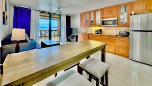 Une cuisine moderne avec des meubles en bois, des appareils électroménagers en acier inoxydable et un coin repas comprenant une table et des bancs.
