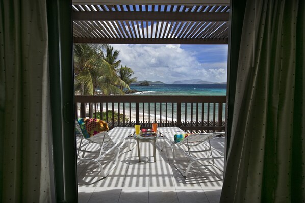 Un balcon avec vue sur l’océan, des palmiers et une pergola en bois.